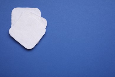 Cotton pads on blue background, flat lay. Space for text