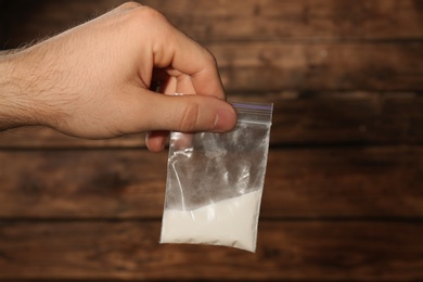 Photo of Man holding plastic bag with cocaine on blurred background, closeup
