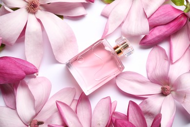 Photo of Beautiful pink magnolia flowers and bottle of perfume on white background, flat lay