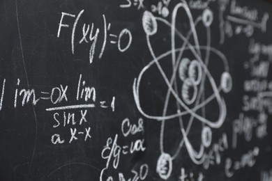 Many different physical formulas written with chalk on blackboard, closeup