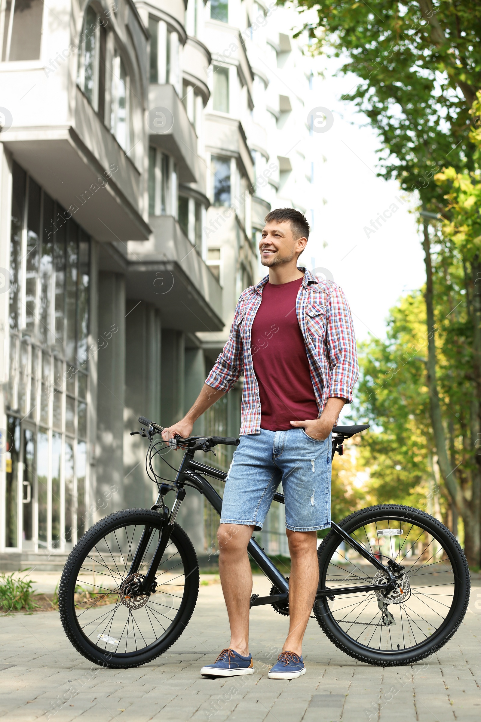 Photo of Handsome man with modern bicycle on city street