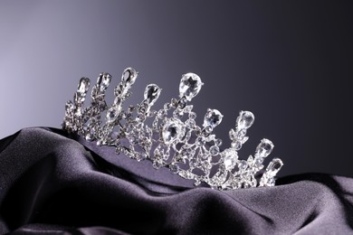 Photo of Beautiful silver tiara with diamonds on dark cloth against grey background