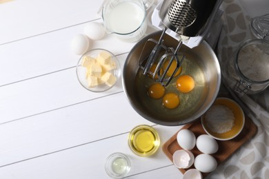 Photo of Making dough. Raw eggs in bowl of stand mixer and ingredients on white wooden table, flat lay with space for text