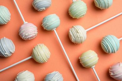 Photo of Sweet cake pops on orange background, flat lay