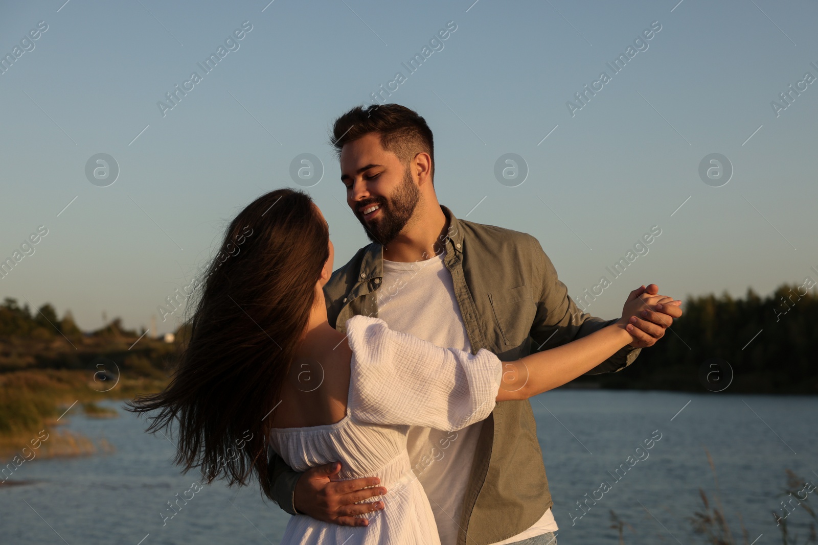 Photo of Beautiful couple dancing near river at sunset