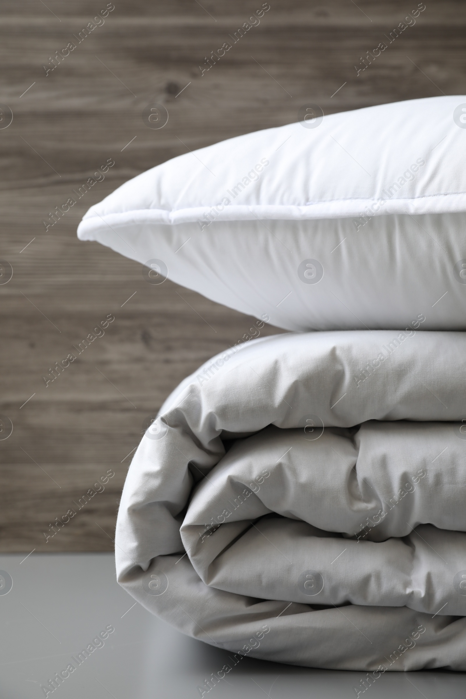 Photo of Soft folded blanket and pillow on light grey table, closeup