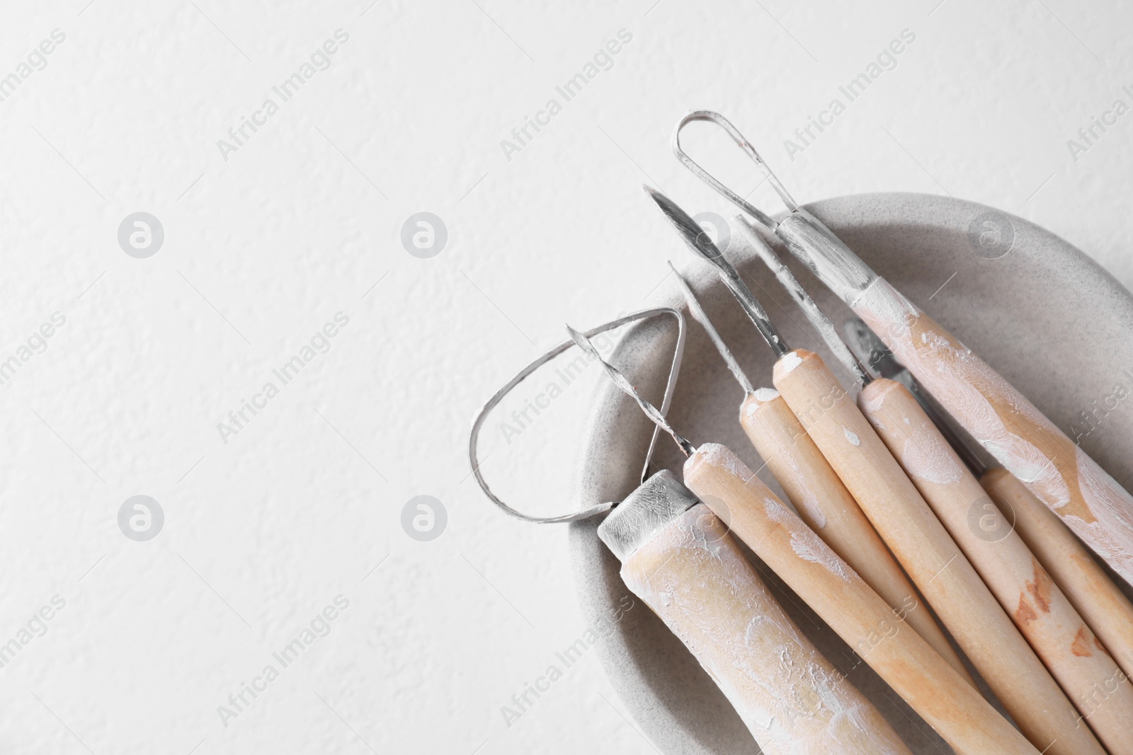 Photo of Set of different clay crafting tools on white table, top view. Space for text