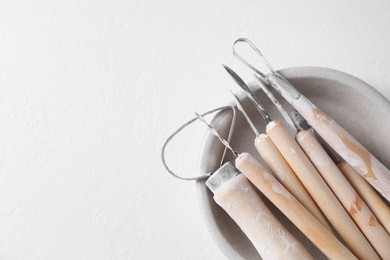 Set of different clay crafting tools on white table, top view. Space for text