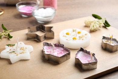 Photo of Different handmade candles and cutters on wooden background