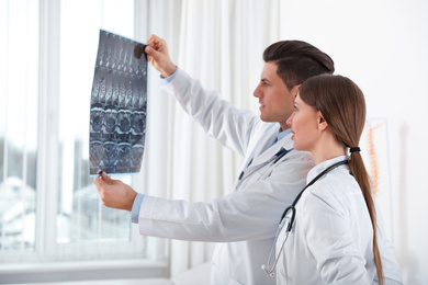 Orthopedists examining X-ray picture near window in office