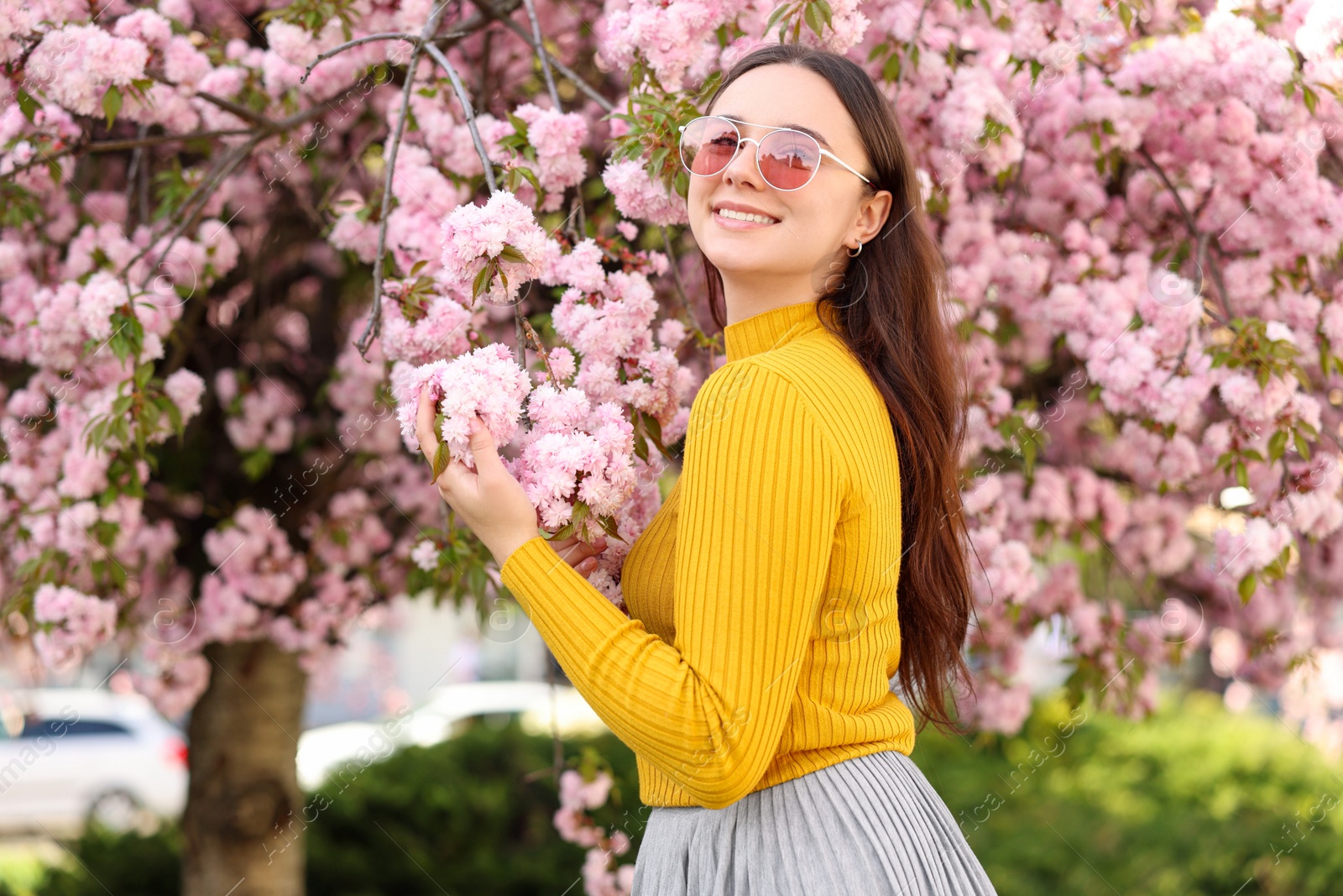 Photo of Beautiful woman in sunglasses near blossoming tree on spring day