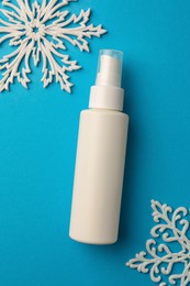 Hand cream and snowflakes on light blue background, flat lay. Winter skin care