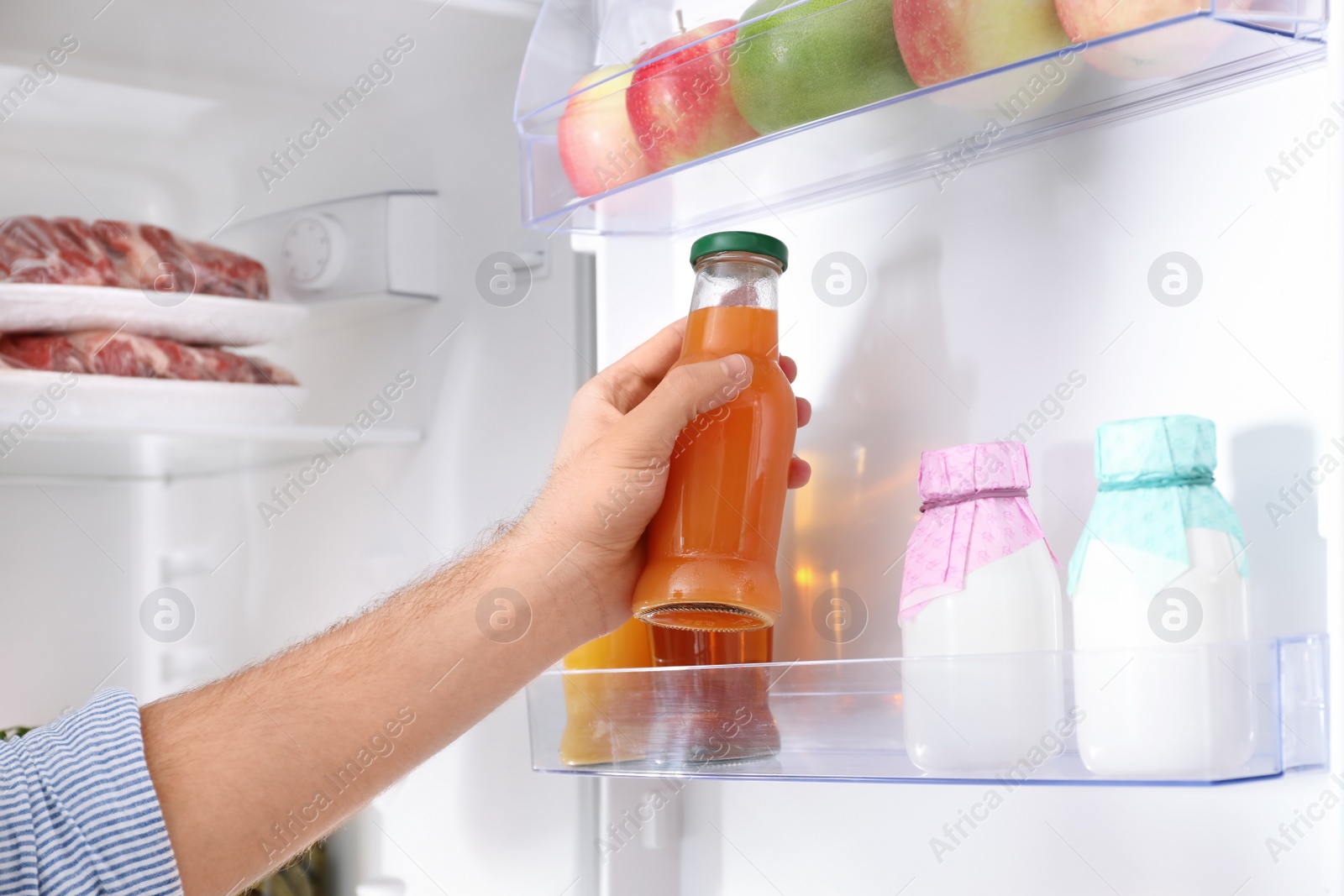 Photo of Man taking bottle with juice out of refrigerator in kitchen, closeup