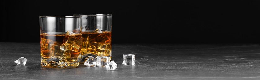 Image of Whiskey in glasses and ice cubes on grey table, space for text. Banner design