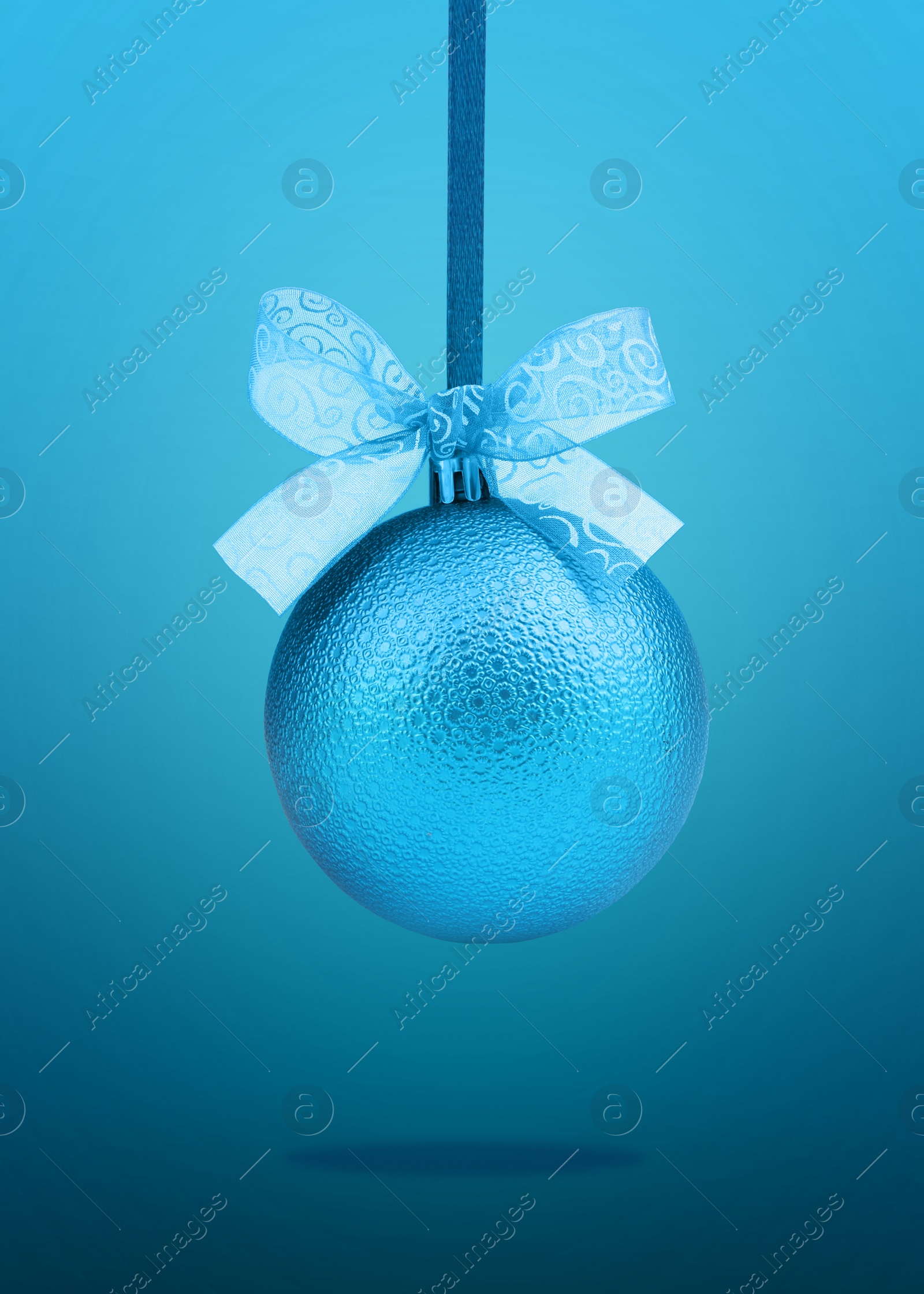 Image of Beautiful Christmas ball with bow hanging on blue background