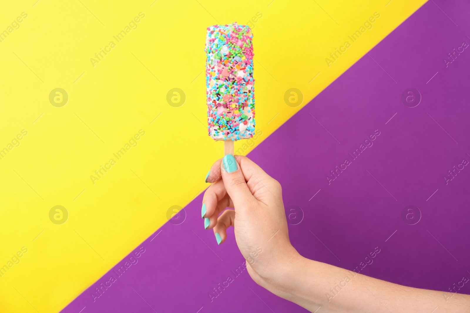 Photo of Woman holding yummy ice cream on color background. Focus on hand