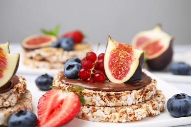 Photo of Tasty crispbreads with chocolate, figs and berries served on light table, closeup