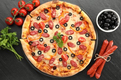 Photo of Tasty pizza with dry smoked sausages, olives, tomatoes, pepper and parsley on grey table, top view