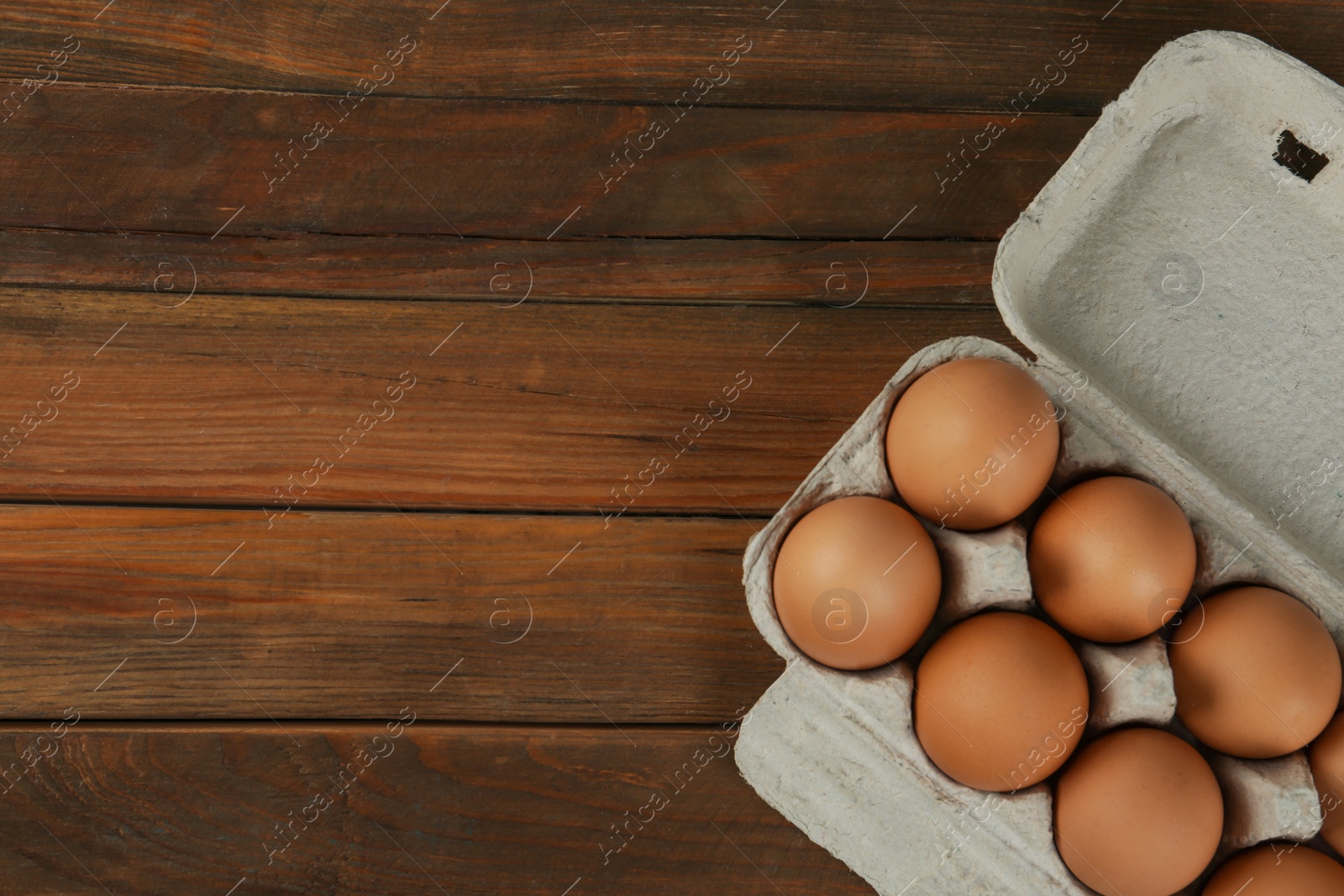 Photo of Raw chicken eggs on wooden table, top view. Space for text