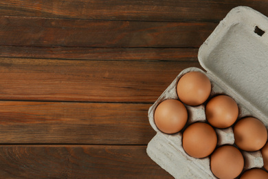 Photo of Raw chicken eggs on wooden table, top view. Space for text