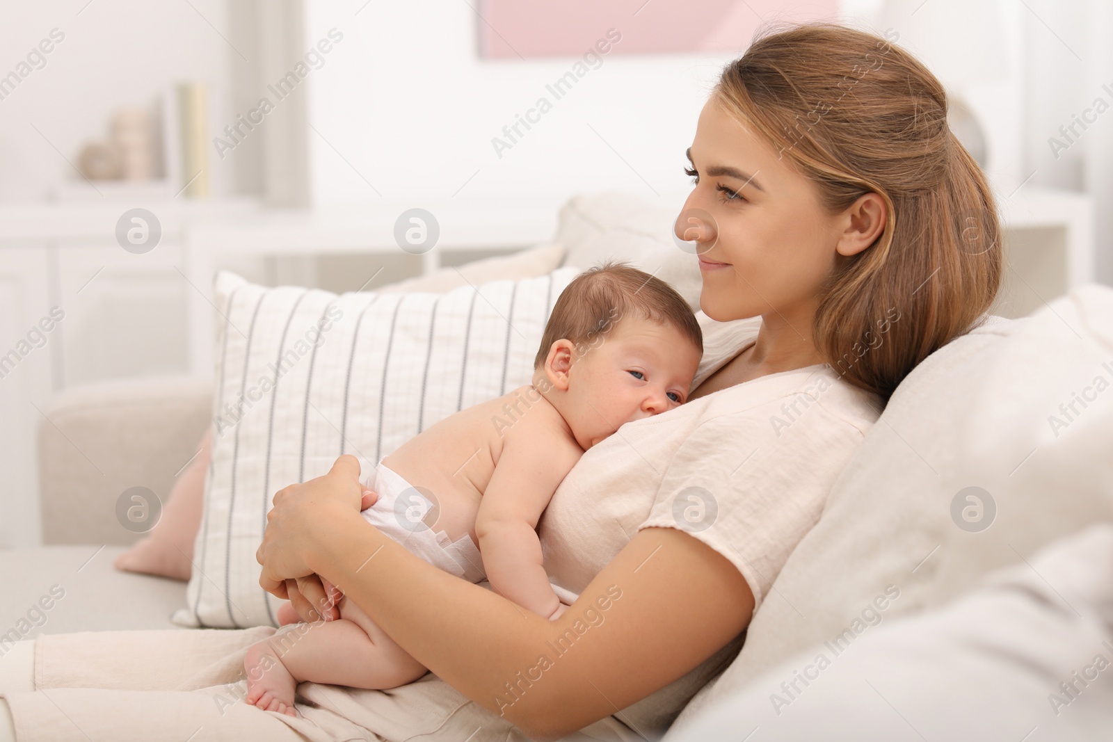 Photo of Mother holding her cute newborn baby on sofa at home, space for text