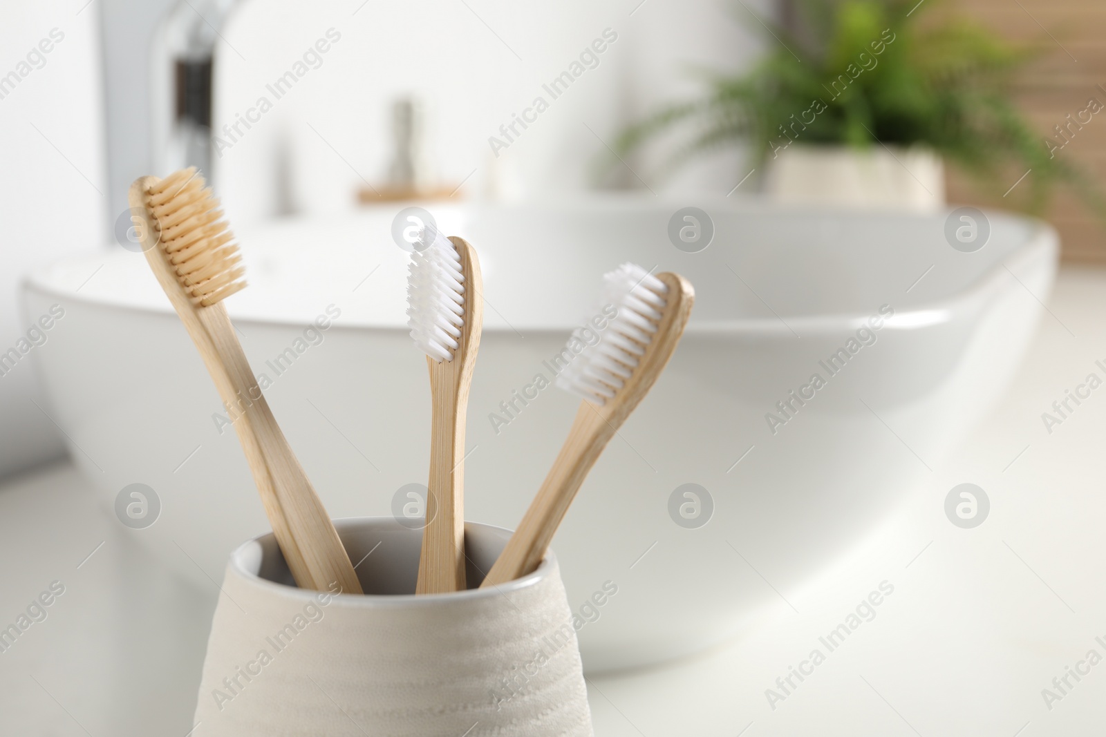 Photo of Bamboo toothbrushes in bathroom, closeup. Space for text