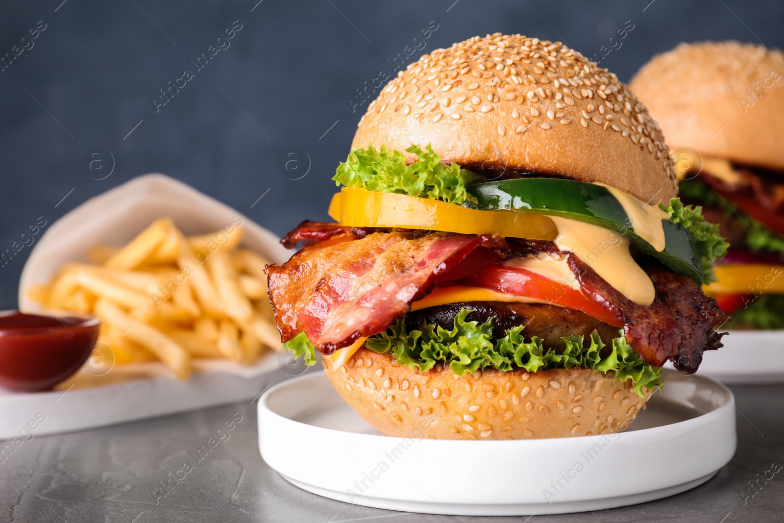 Photo of Composition with juicy bacon burger on grey table