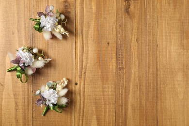Photo of Stylish boutonnieres on wooden table, flat lay. Space for text