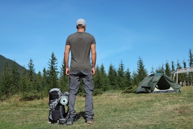 Photo of Tourist with backpack in mountains on sunny day, back view. Space for text