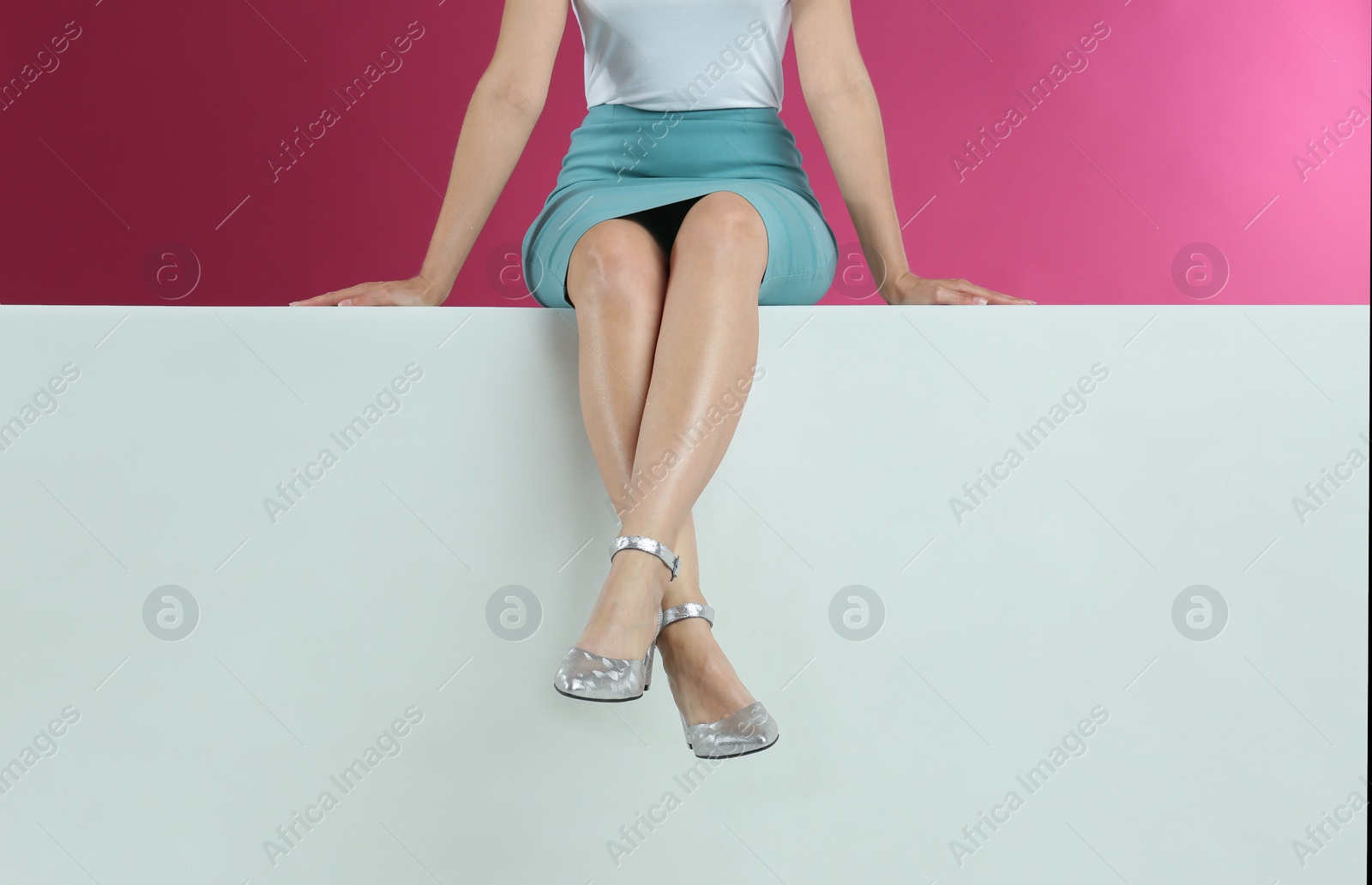 Photo of Woman in stylish shoes sitting on color background, closeup