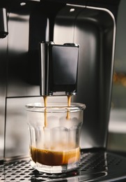 Photo of Espresso machine pouring coffee into glass, closeup