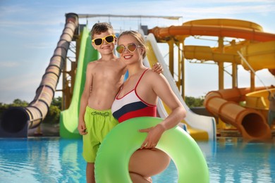 Photo of Son and mother with inflatable ring near pool in water park. Family vacation