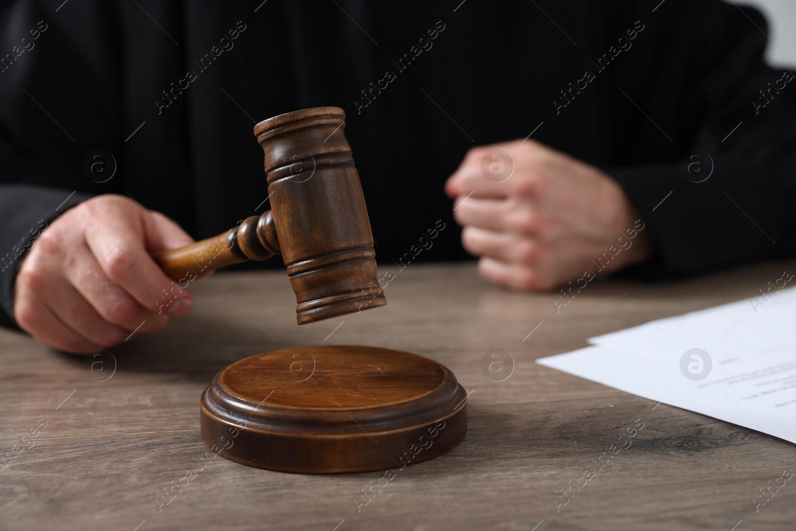 Photo of Judge with gavel and papers at wooden table, closeup