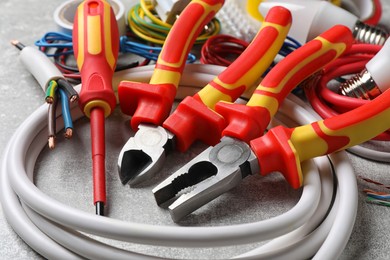 Set of electrician's tools and accessories on grey background, closeup