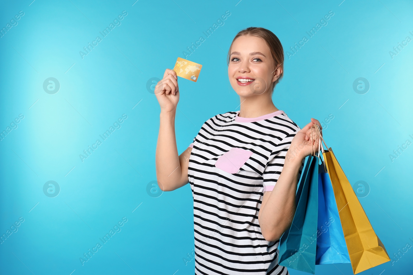 Photo of Portrait of happy young woman with credit card and shopping bags on color background, space for text. Spending money