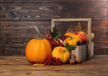 Photo of Happy Thanksgiving day. Composition with pumpkins, berries and walnuts on wooden table