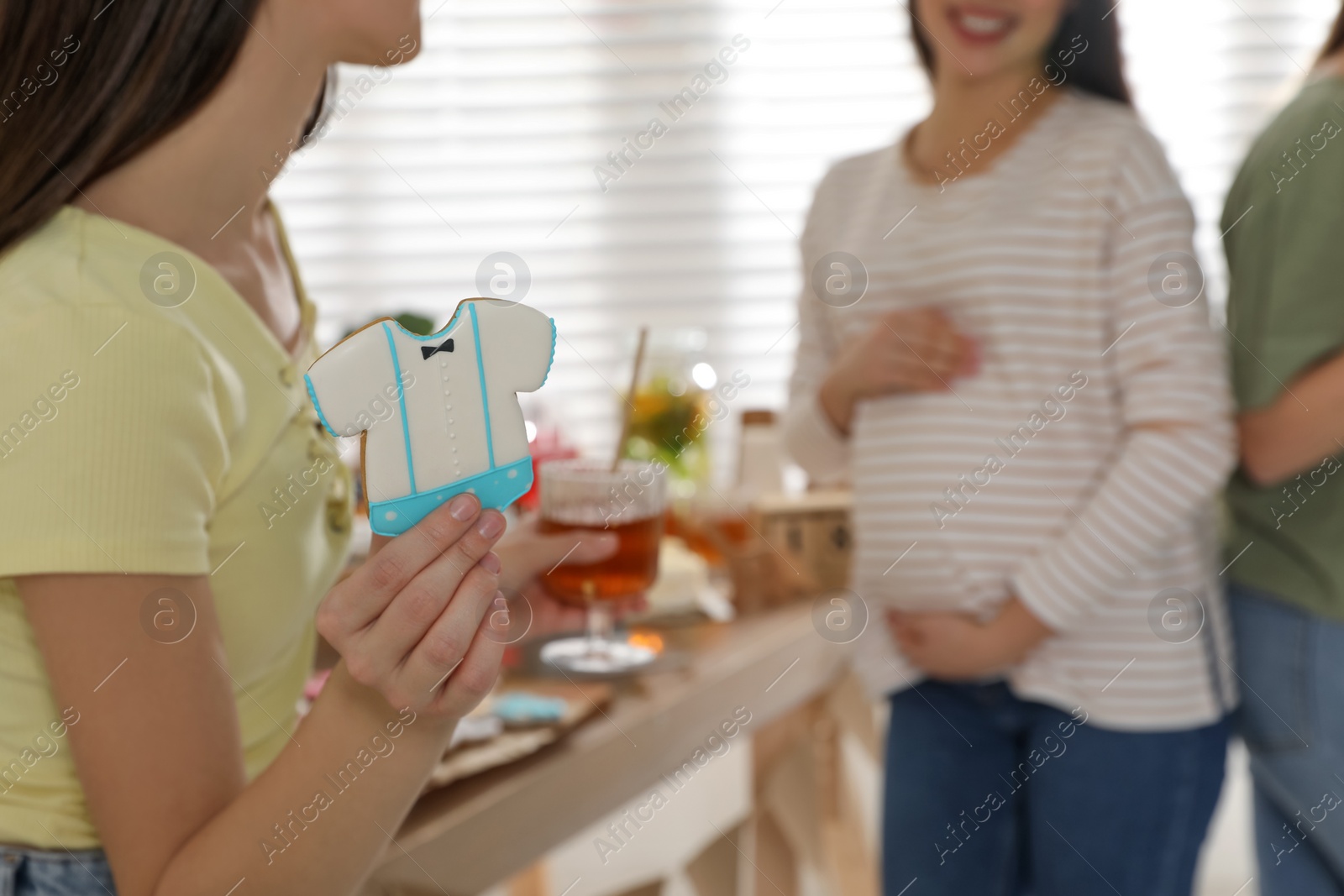 Photo of Woman with tasty cookie at baby shower party, closeup. Space for text