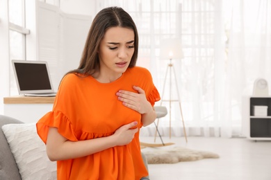 Young woman suffering from heart attack at home