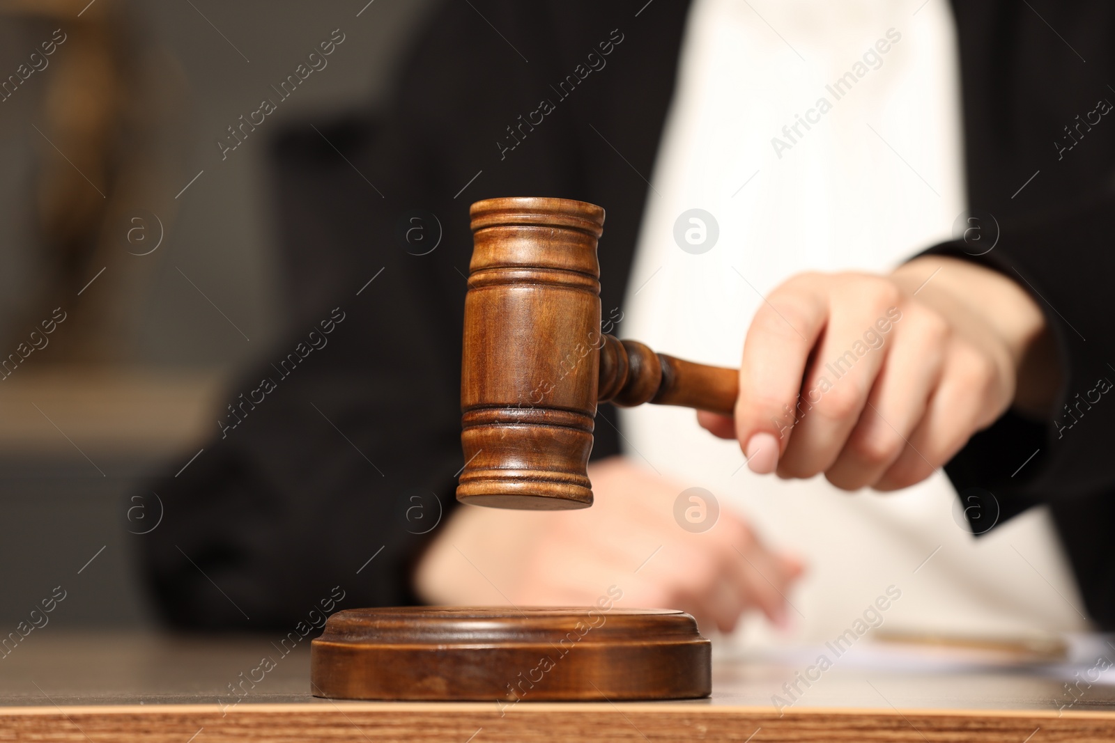 Photo of Judge striking mallet at wooden table in courtroom, closeup