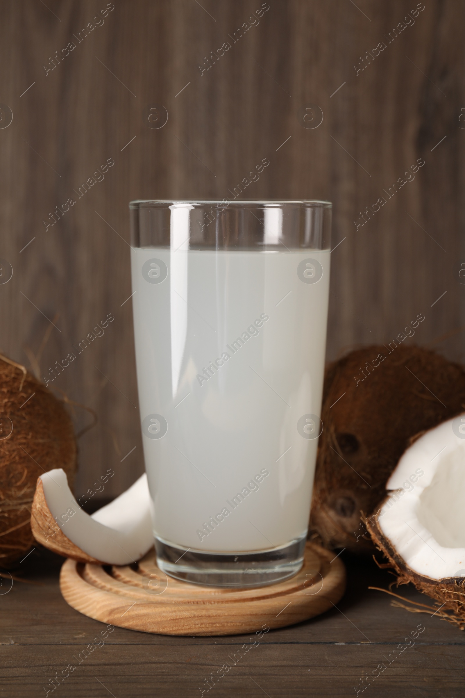 Photo of Glass of coconut water and nuts on wooden table