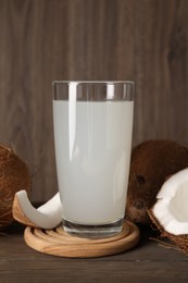 Photo of Glass of coconut water and nuts on wooden table