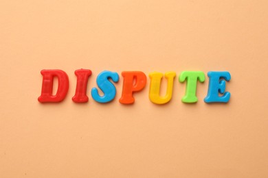 Word Dispute made of colorful letters on pale orange background, flat lay