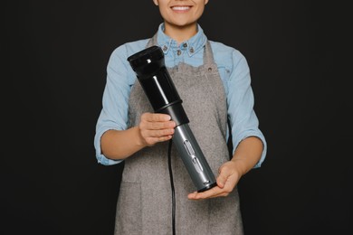 Woman holding sous vide cooker on black background, closeup