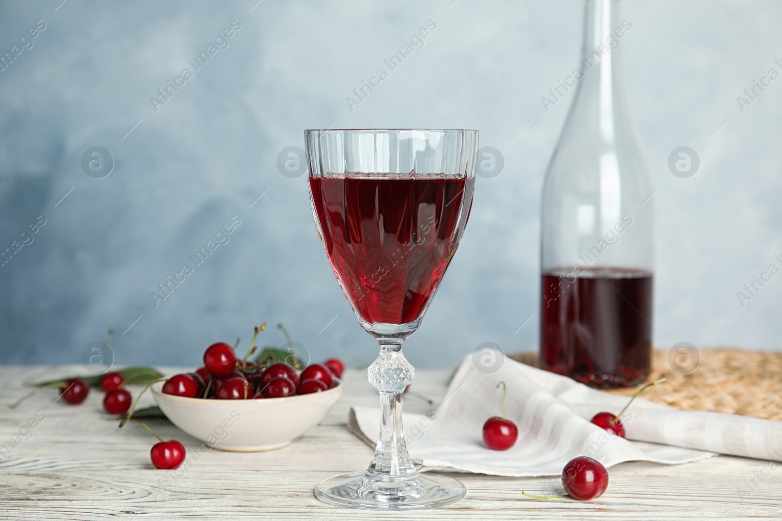 Photo of Delicious cherry wine with ripe juicy berries on white wooden table