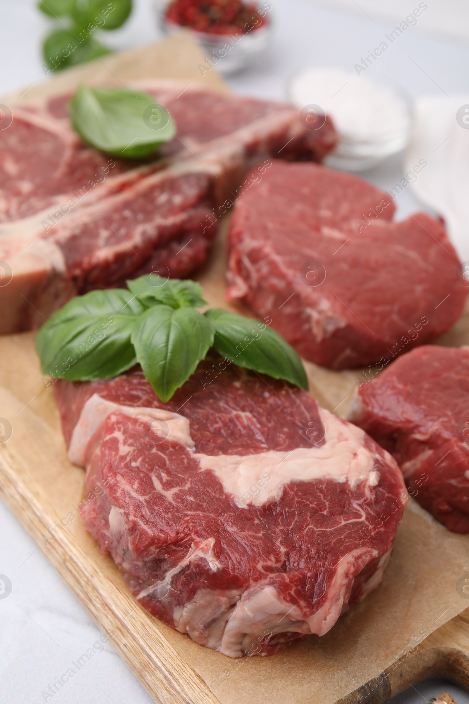 Photo of Cut fresh beef meat with basil leaves on wooden board, closeup