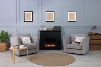 Black stylish fireplace near comfortable armchairs in cosy living room