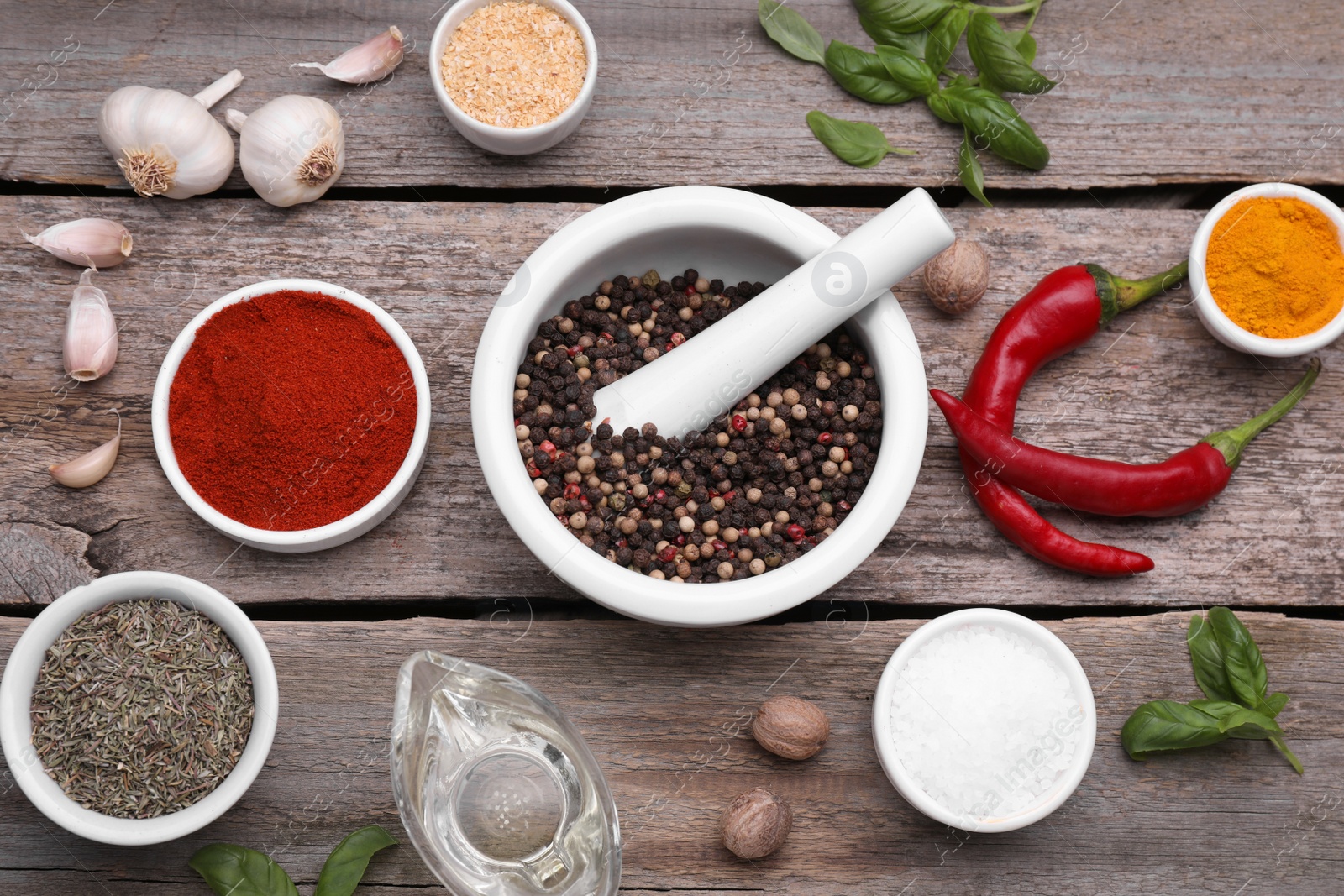 Photo of Mortar with pestle and different spices on wooden table, flat lay