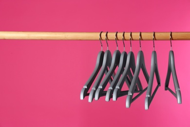 Wooden rack with clothes hangers on color background, space for text