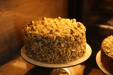 Delicious cake with nuts on counter in bakery shop, closeup