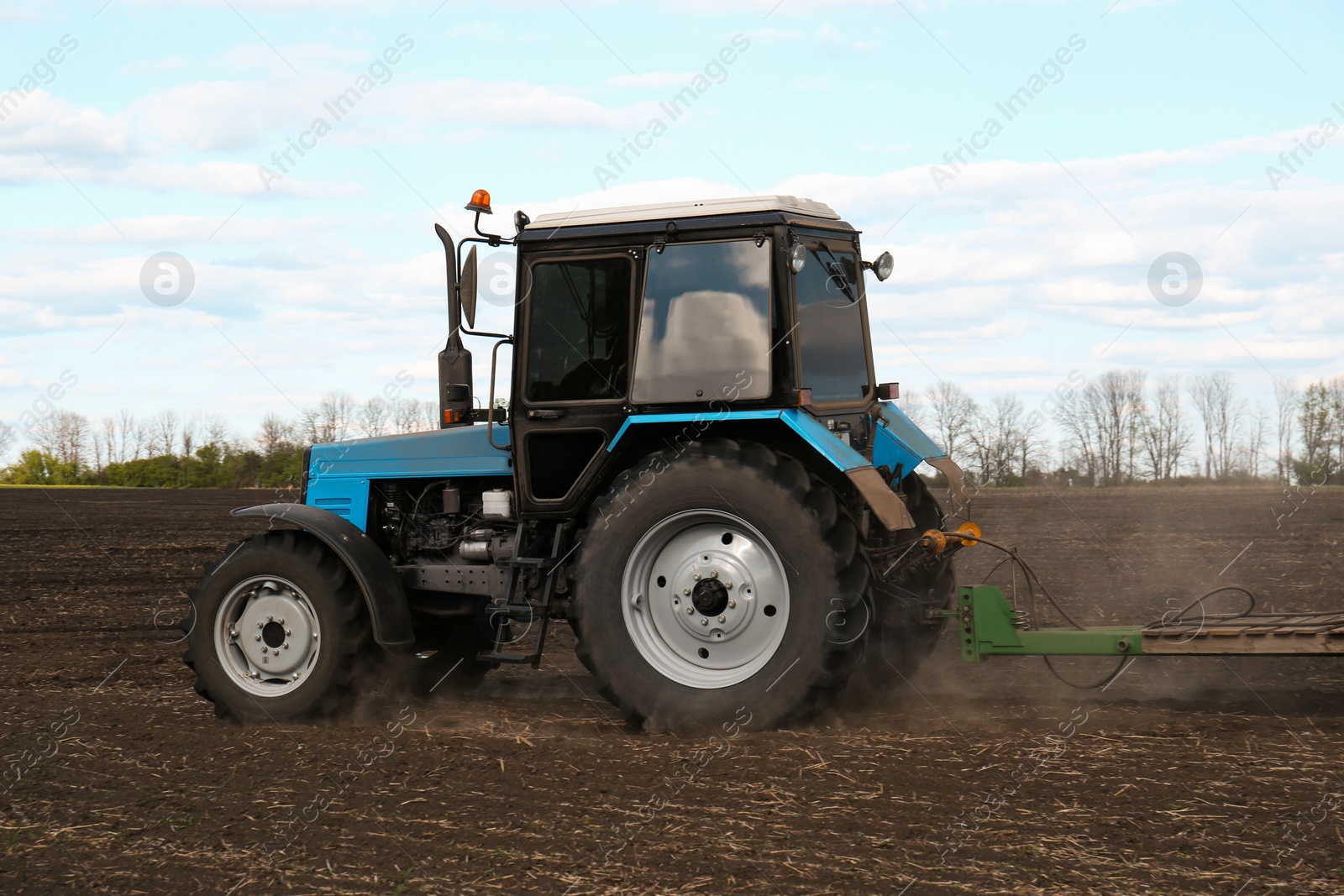 Photo of Tractor with planter cultivating field on sunny day. Agricultural industry